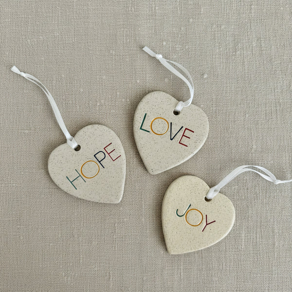 Three heart-shaped tags with 'Hope', 'Love', and 'Joy' on a white background