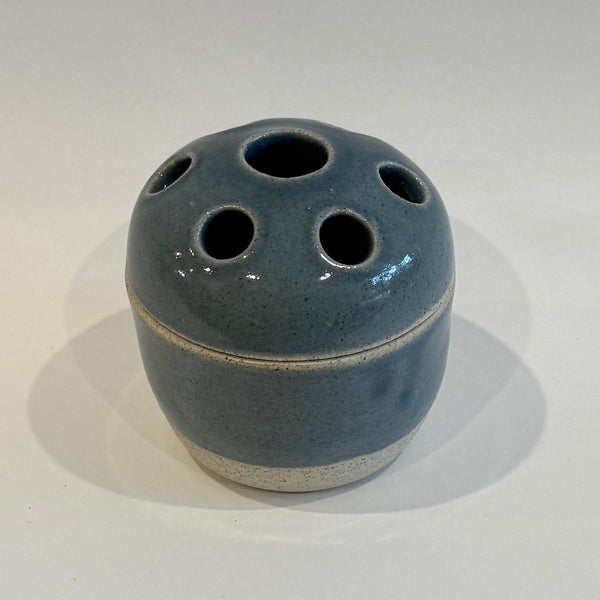 Lidded Blue ceramic vase with multiple holes on a white background