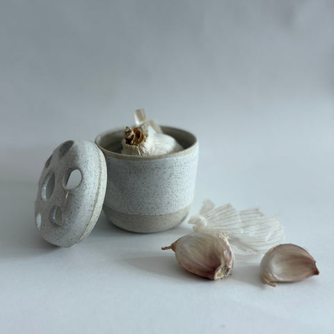 Lidded Ceramic container with garlic on a white background. Garlic Holder or flower frog